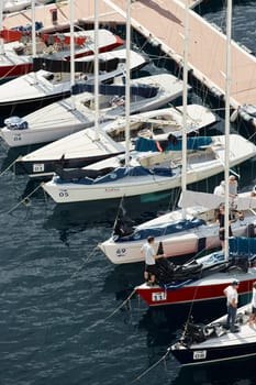 Monaco, Monte-Carlo, 29 September 2022: a lot of sail boats are moored in the new Yacht Club at sunny day, no wind, teams is waiting race, port Hercules, bow with sails. High quality photo