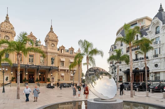 Monaco, Monte-Carlo, 21 October 2022: Square Casino Monte-Carlo at sunny day, a lot of luxury cars, Hotel de Paris, wealth life, tourists take pictures of the landmark, pine trees, blue sky, flowers. High quality 4k footage