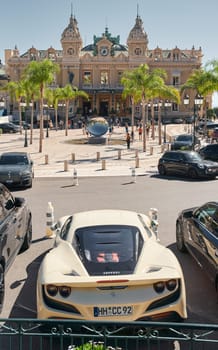 Monaco, Monte-Carlo, 22 October 2022: Square Casino Monte-Carlo at sunset, luxury cars, famous Hotel de Paris, wealth life, tourists take pictures of the landmark, pine trees, flowers. High quality photo