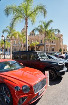 Monaco, Monte-Carlo, 22 October 2022: Square Casino Monte-Carlo at sunset, luxury cars, famous Hotel de Paris, wealth life, tourists take pictures of the landmark, pine trees, flowers. High quality photo