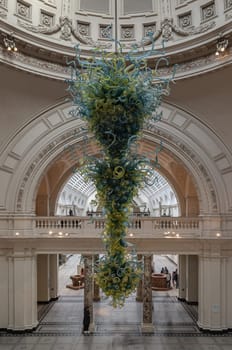 London, UK - Nov 01, 2023 - Metre high, View of Blown glass chandelier in Victoria and Albert Museum hall. Beautiful interior architecture design of The Victoria & Albert Museum. Inner decor, Space for text, Selective focus.