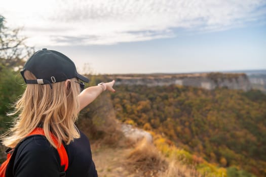 woman on mountain peak looking in beautiful mountain valley in autumn. Landscape with sporty young woman, blu sky in fall. Hiking. Nature.