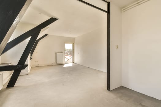 an empty room with white walls and black metal beams on the wall, there is a window in the corner