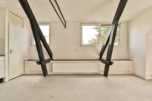 an empty room with white walls and black metal beams on the ceiling, there is a small window in the corner