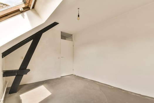 an empty room with white walls and black metal staircase leading up to the second floor, which is being used for storage