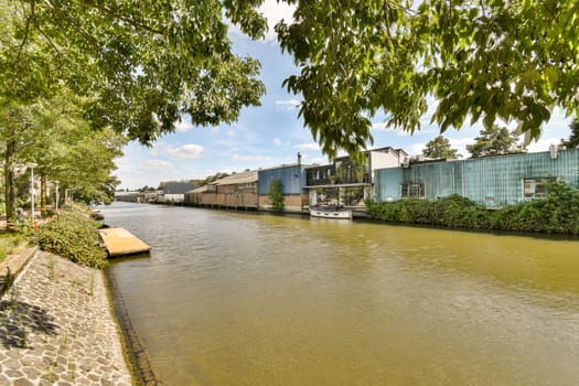 a river with buildings and trees in the fore, taken from a boat on the water's edge as it passes by