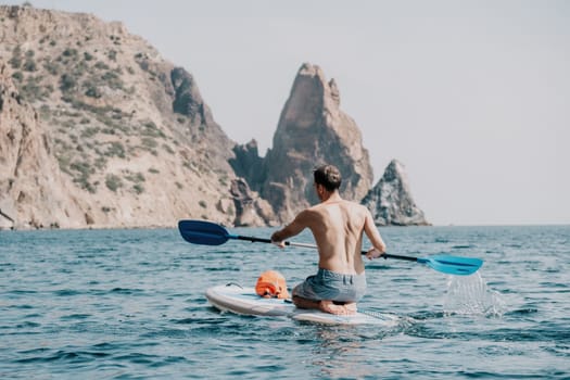 Side view foto of a man swiming and relaxing on the sup board. Sportive man in the sea on the Stand Up Paddle Board SUP. The concept of an active and healthy life in harmony with nature