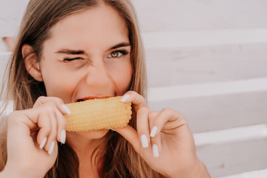 Healthy vegetarian hipster woman in summer outfit eat grilled corn and look to camera. Sexy lady on sea beach sunset or ocean sunrise. Travel, explore, active yoga and meditation lifestyle concept.