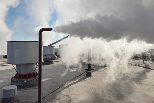 steam emission from a pipe on the roof against a blue sky background. photo