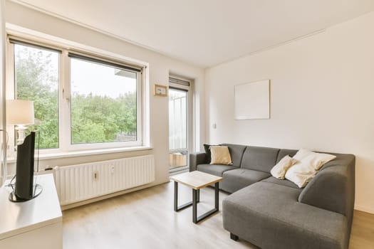 a living room with wood flooring and large windows looking out onto the trees outside in the photo is taken from inside