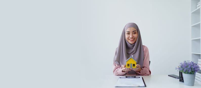 A female Muslim bank employee, making an agreement on a residential loan with a customer