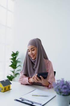 muslim woman with hijab using calculator focus on utility bills calculate check credit card receipt monthly expense