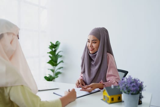 A female Muslim bank employee, making an agreement on a residential loan with a customer