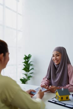 A female Muslim bank employee, making an agreement on a residential loan with a customer