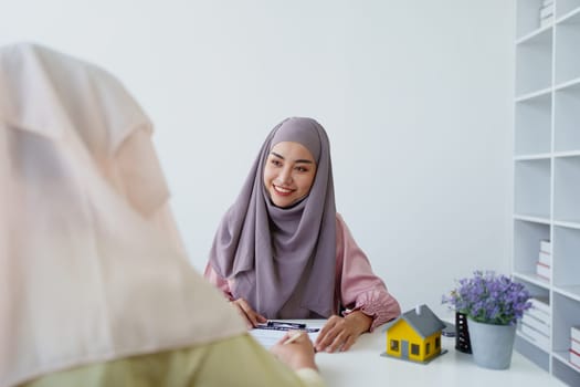 A female Muslim bank employee, making an agreement on a residential loan with a customer