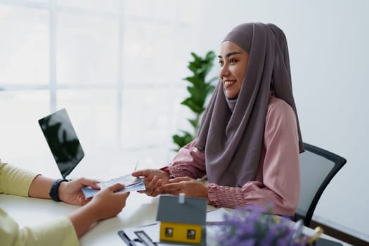A female Muslim bank employee, making an agreement on a residential loan with a customer
