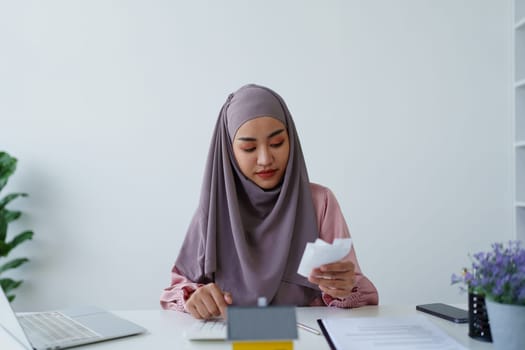 muslim woman with hijab using calculator focus on utility bills calculate check credit card receipt monthly expense