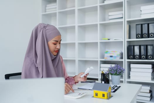 muslim woman with hijab using calculator focus on utility bills calculate check credit card receipt monthly expense