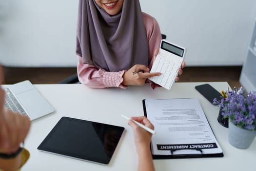 A female Muslim bank employee, making an agreement on a residential loan with a customer