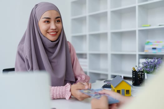 A female Muslim bank employee, making an agreement on a residential loan with a customer