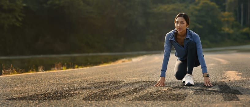 Determined athlete woman in starting position on road with numbers 2024, getting ready for the new year.