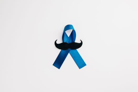 A top view of a blue ribbon with a mustache, symbolizing support for men, isolated on a white background. Perfect for healthcare, research, and awareness events.