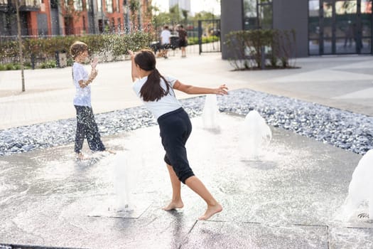 life of children in a modern city - little girl having fun with fountains. High quality photo