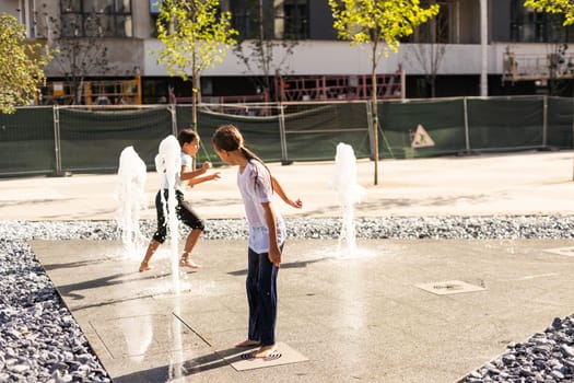 On a hot day, children run and have fun at the city fountain. Leisure time concept. summer holidays. happy childhood. High quality photo