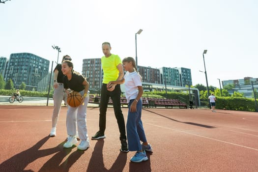 summer holidays, sport and people concept - happy family with ball playing on basketball playground. High quality photo