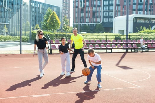 summer holidays, sport and people concept - happy family with ball playing on basketball playground. High quality photo