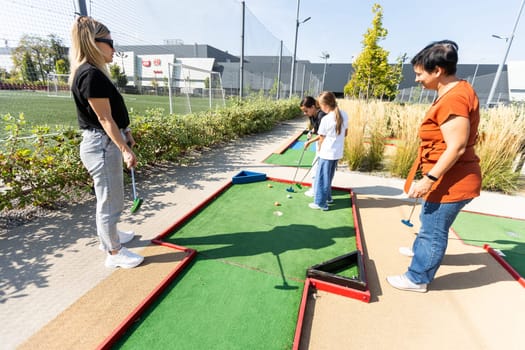 Mother and her little daughter practicing to hit the ball at the course. High quality photo