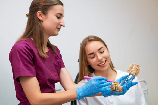 A dental hygienist provides a practical demonstration to a young woman on the proper technique for cleaning teeth