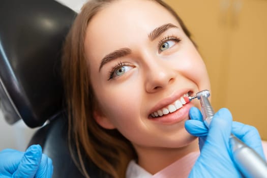 Woman patient sitting in medical chair during teeth grinding procedure.