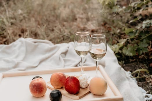 Picnic and wine tasting at sunset in the hills of Italy, Tuscany. Vineyards and open nature in the summer. Romantic dinner, fruit and wine.