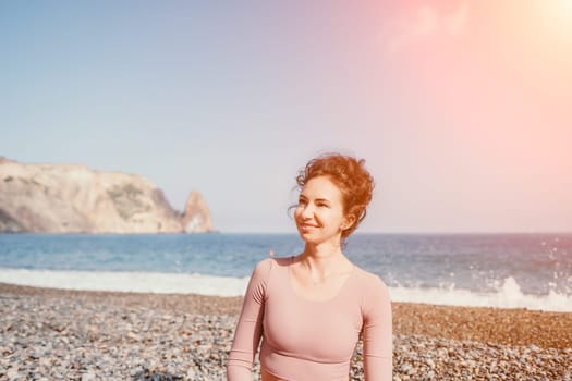 Middle aged well looking woman with black hair doing Pilates with the ring on the yoga mat near the sea on the pebble beach. Female fitness yoga concept. Healthy lifestyle, harmony and meditation.