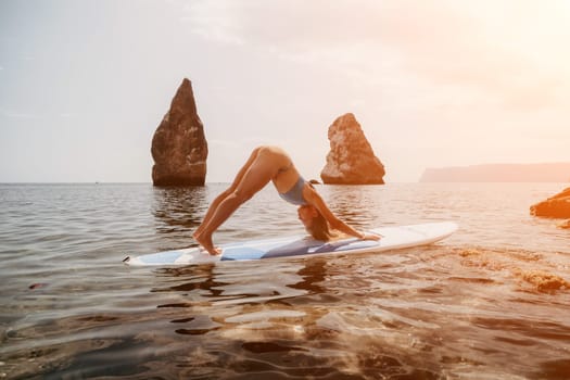 Woman sup yoga. Middle age sporty woman practising yoga pilates on paddle sup surfboard. Female stretching doing workout on sea water. Modern individual hipster outdoor summer sport activity