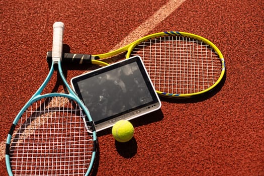 sport, fitness, technology, game and objects concept - close up of tennis racket with ball and tablet pc computer High quality photo