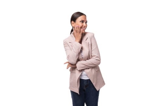 young pleasant brunette woman dressed in a beige jacket smiles and laughs on a white background with copy space.