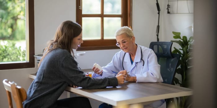 Medicine, healthcare and people concept female doctor with medicine bottle talking to women patient at hospital.