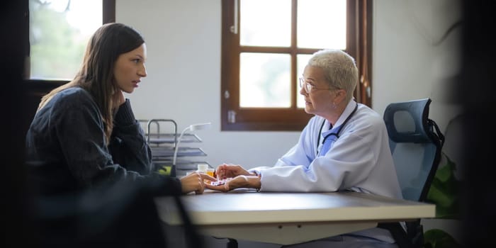 Medicine, healthcare and people concept female doctor with medicine bottle talking to women patient at hospital.