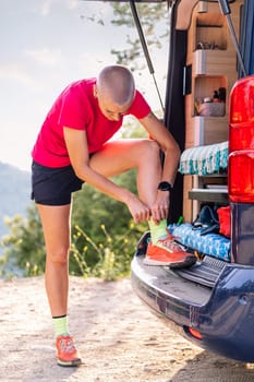 woman in a camper van preparing to trail running and do sports in nature, concept of outdoor activities and healthy lifestyle