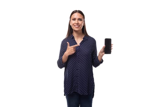 young brunette business woman dressed in a blue shirt shows a smartphone with a mockup.