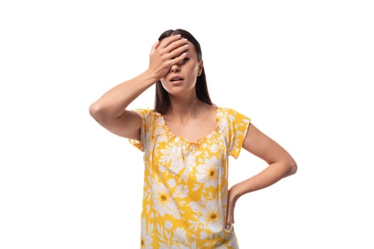 Caucasian young woman with straight black hair dressed in a yellow sundress concentrated on thought.