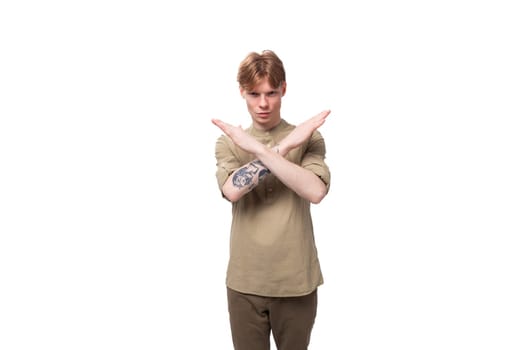 a young European man with red golden hair dressed in a light brown shirt gesticulates on a white background. advertising concept.