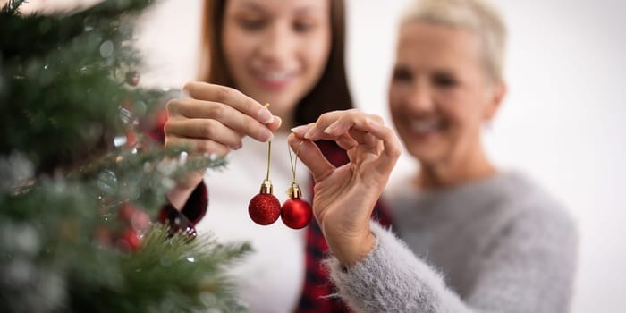 Family winter holiday and concept happy senior woman with adult daughter decorate christmas tree at home.