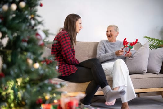 Senior woman with adult daughter enjoying time at home on Christmas eve.
