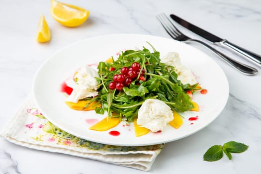 arugula salad with peach slices and red berries on a white plate