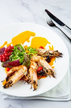 cooked shrimp with herbs and berries on a white plate