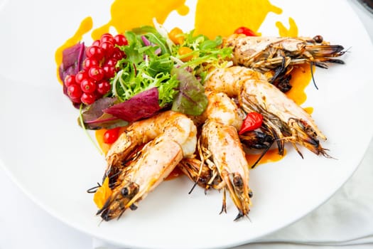 cooked shrimp with herbs and berries on a white plate