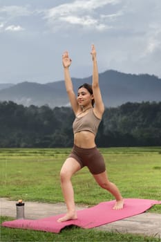 Asian woman sporty practicing yoga at public park outdoor stretching her body. Healthy active lifestyle.